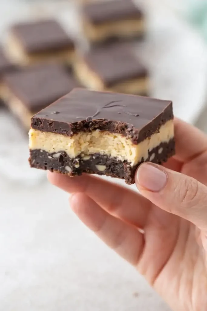 Close-up of Nanaimo bar squares on a plate, highlighting the rich chocolate top layer and smooth custard center